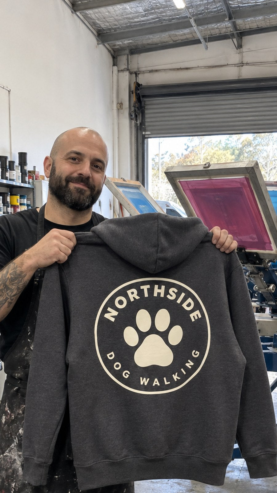 Print shop owner holding up the dog walker hoodie in the shop