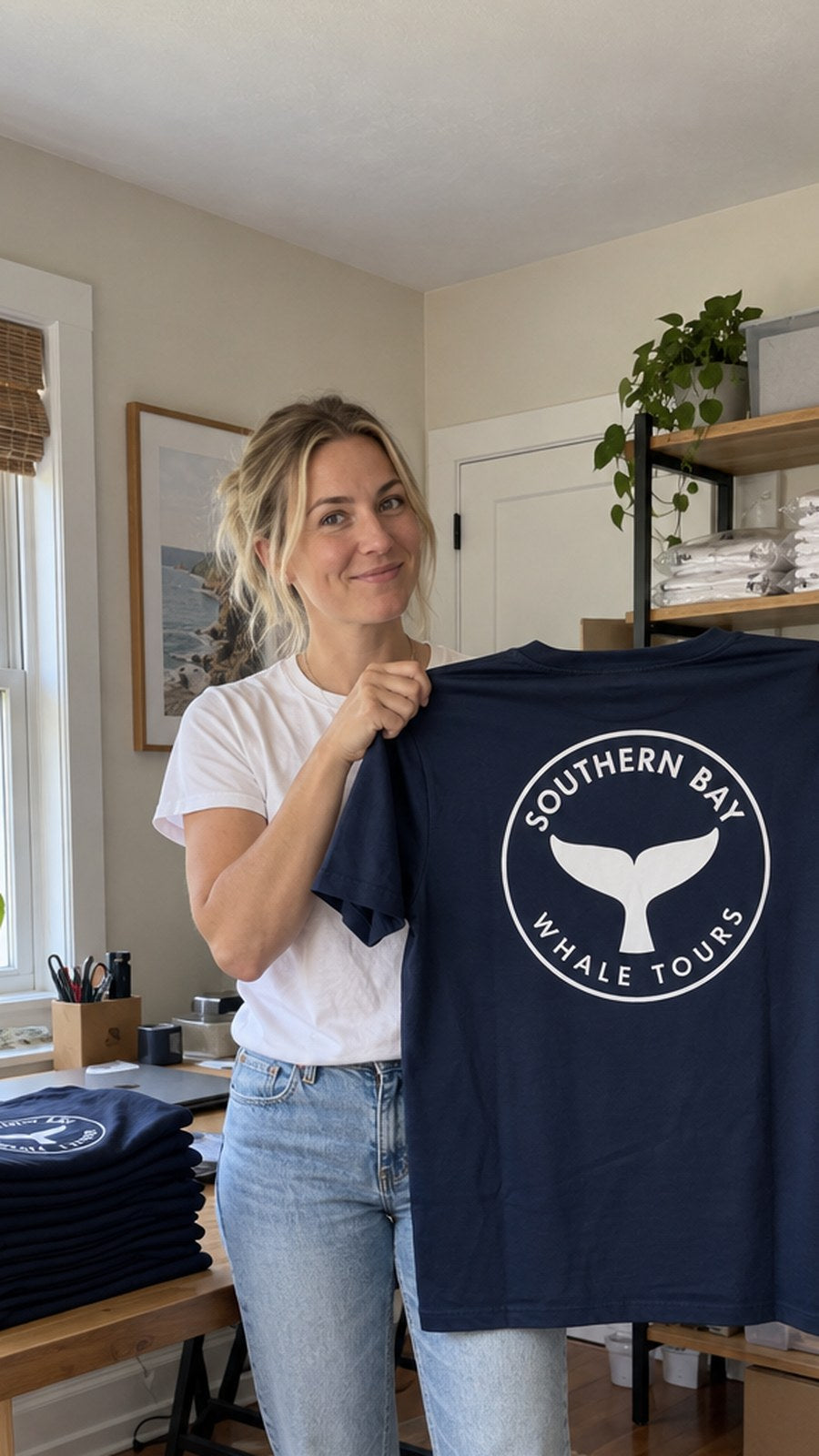 Holding up the whale tee in the booking office