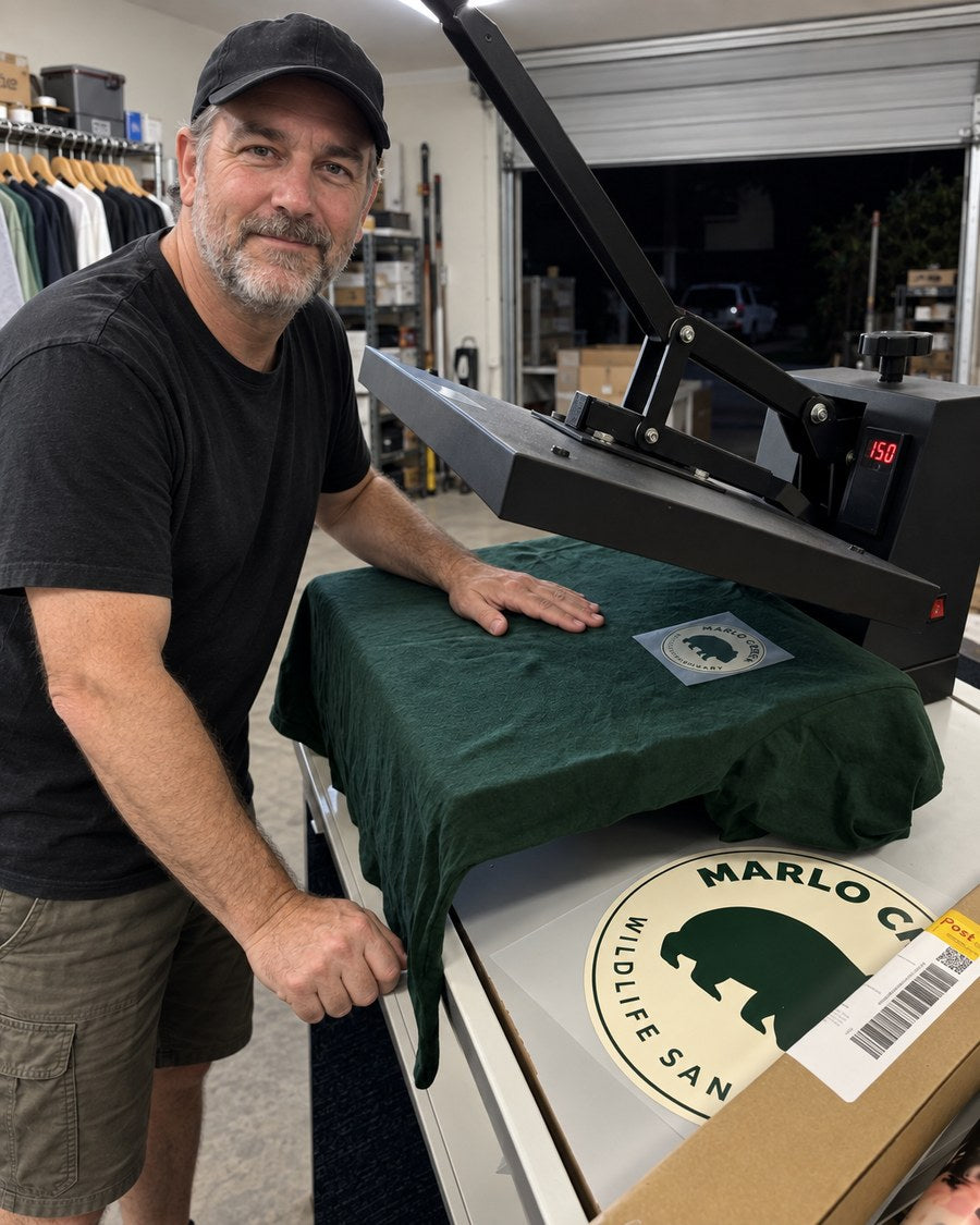 Smoothing the tee on the heat press with the badge transfer in place